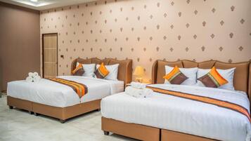 A hotel room with two beds, each with white linens and orange accents, a wooden door, and patterned wallpaper.