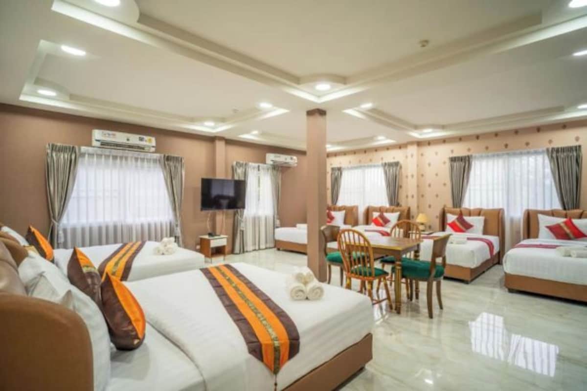 A hotel room with two beds, a dining area, and a TV.