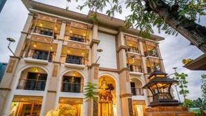A multi-story building with ornate balconies and a central entrance with a statue.