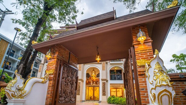 A traditional Thai building with ornate golden decorations, a covered entrance, and a central Buddha statue.