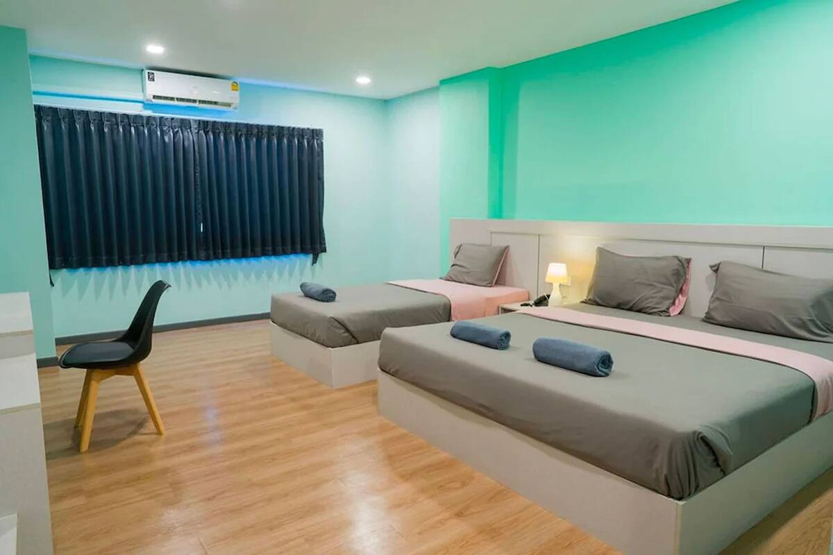 A hotel room with two beds, a desk, a chair, and a window with curtains.