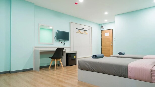 Un dormitorio moderno con escritorio, cama y televisor.