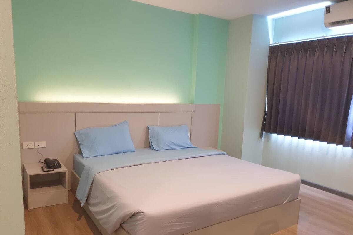 A bedroom with a bed, a nightstand, and a wall-mounted air conditioner.