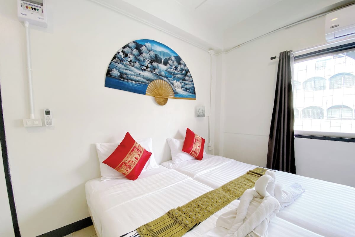 A hotel room with a bed, a painting, and a window with curtains.