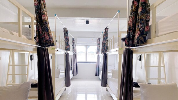 A corridor with bunk beds, each with a curtain and a pillow. - Remember @ Phuket Town Hostel (Phuket)