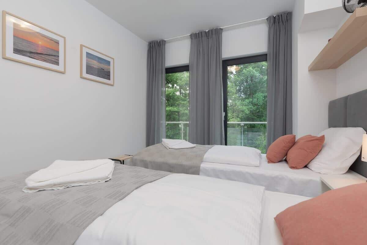 Une chambre d’hôtel avec deux lits, une grande fenêtre avec des rideaux et des œuvres d’art accrochées au mur.