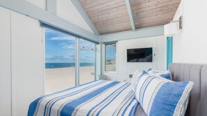 A bedroom with a large bed, a TV, and a view of the beach.