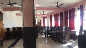 A spacious room with multiple tables and chairs, ceiling fans, and a tiled floor. - Valley View Inn (Nainital)
