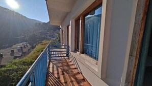 A balcony with a checkered floor, a blue railing, and large windows overlooking a mountainous landscape. - Valley View Inn (Nainital)