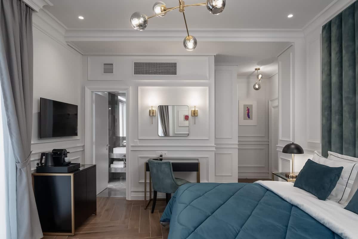 Una habitación de hotel moderna con una cama grande, un escritorio, un televisor y un baño visible a través de una puerta abierta.