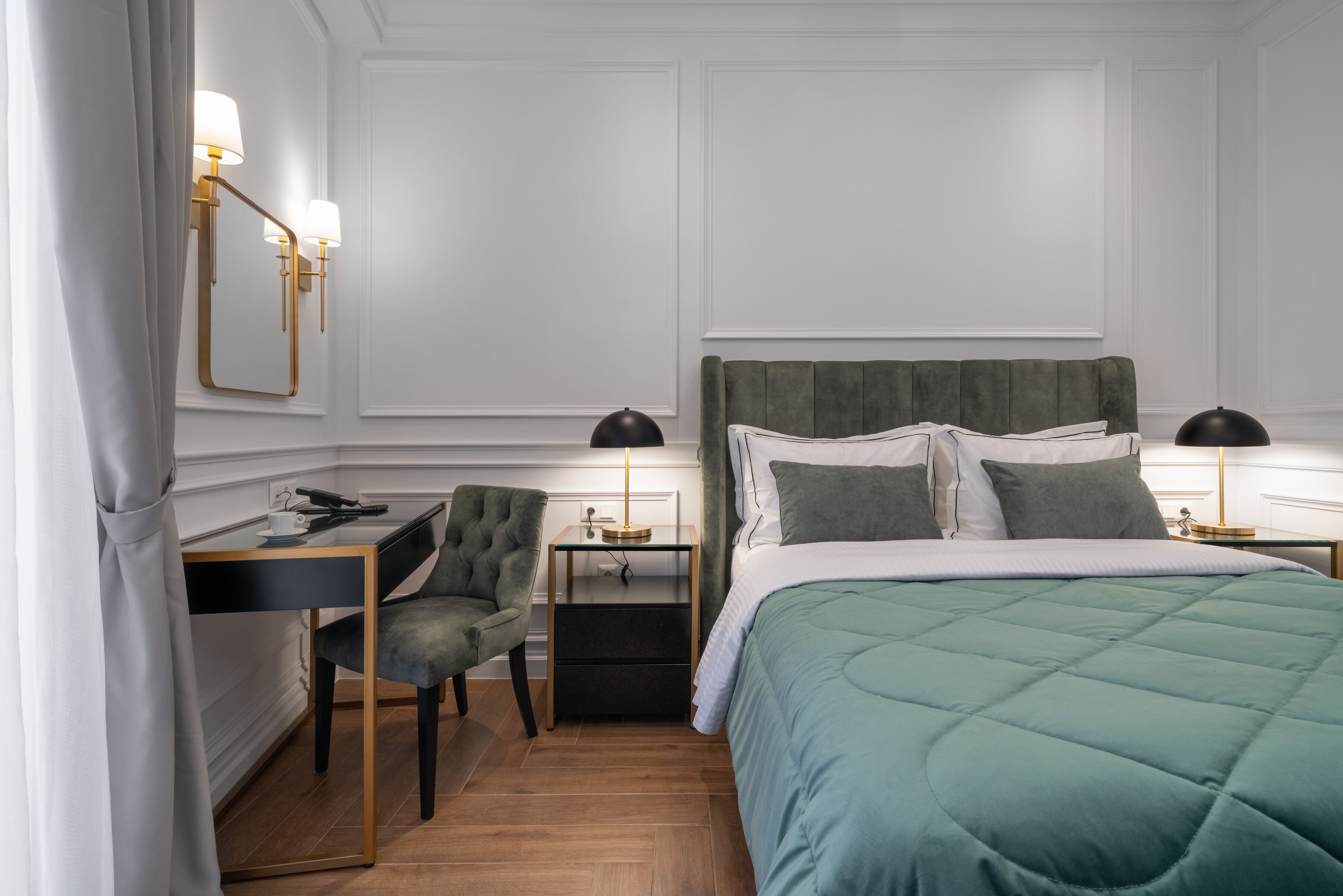 Habitació d'hotel amb un llit, escriptori, cadira i dues taules de nit amb làmpades.