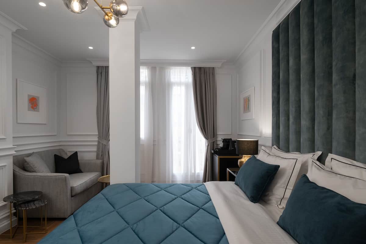 Habitación de hotel con una cama grande, un sofá, una mesita y un escritorio con lámpara.