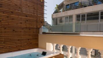 A wooden deck with a hot tub and steps leading to a balcony.