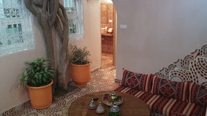 Een gezellig interieur met een patroon vloer, een houten tafel met decoratieve objecten, een bank met een gestreept kussen en een kamerplant.