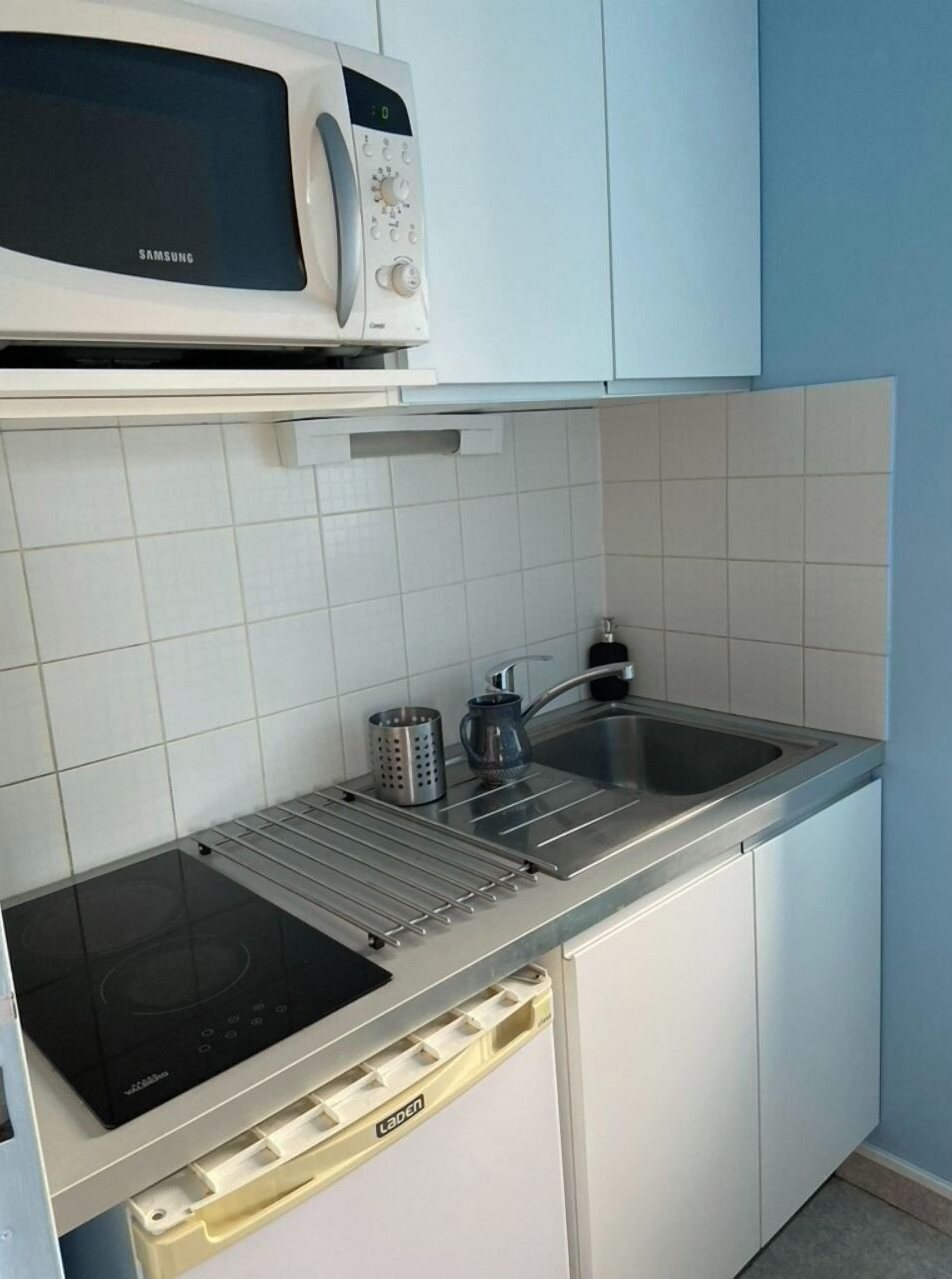 Una cocina compacta equipada con microondas, pileta y placa de inducción integrada.