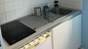 Una cucina compatta con forno a microonde, lavello e piano cottura a induzione integrato.
