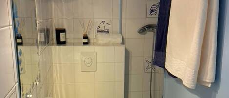 A bathroom with a white sink, a mirror, a shower with a glass door, and a towel rack with a blue towel.