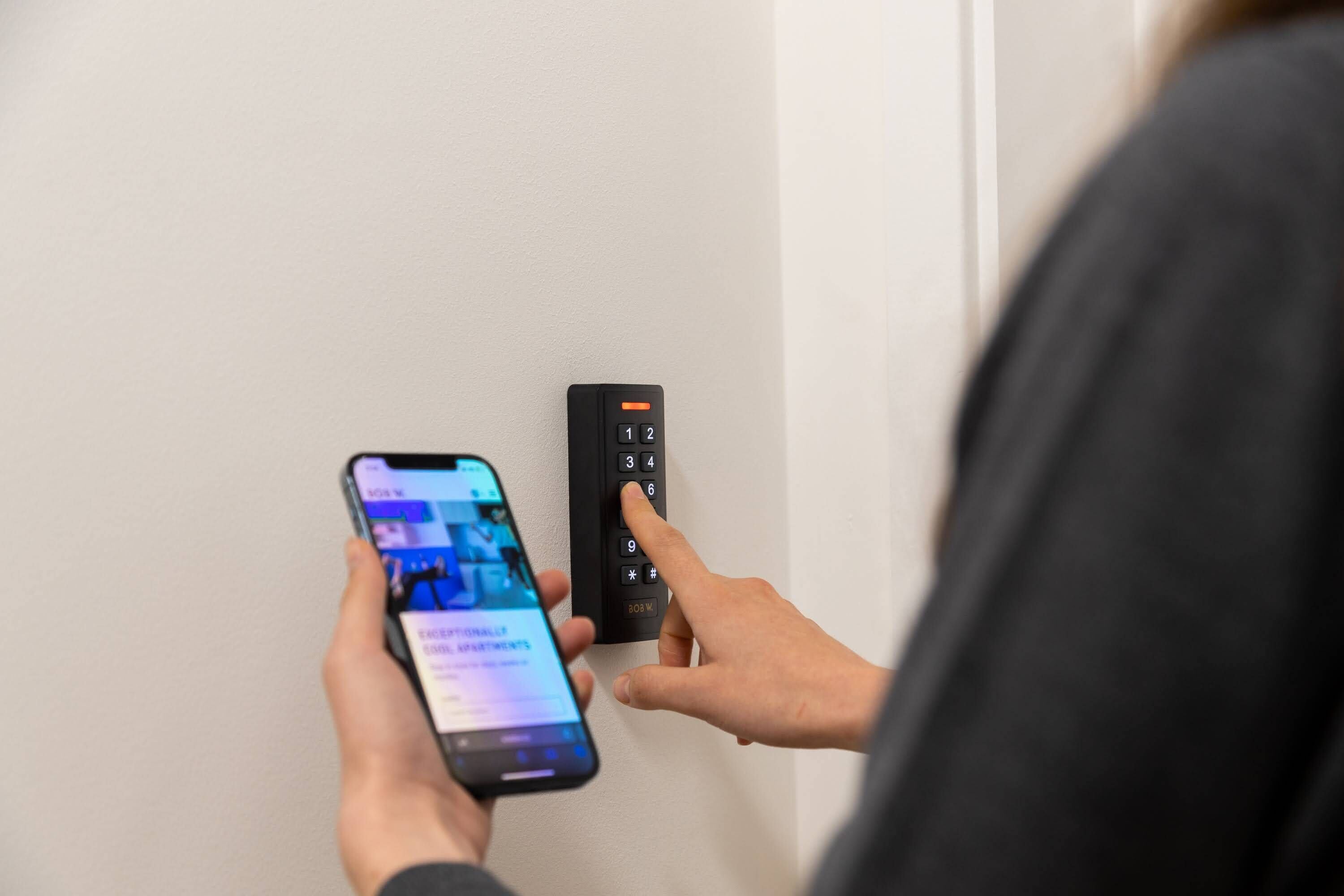 A person using a smartphone and a keypad to enter a room.