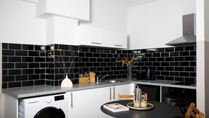 Une cuisine moderne avec des carreaux noirs et blancs, un lave-linge encastré et un coin repas comprenant une table et des chaises.