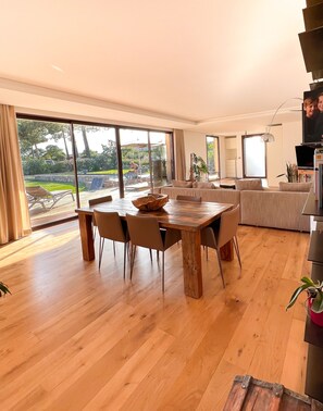 A spacious living room with a wooden dining table, a sofa, and a TV. - New villa in St. Cyprien, just a few minutes' walk from the beach (Lecci)