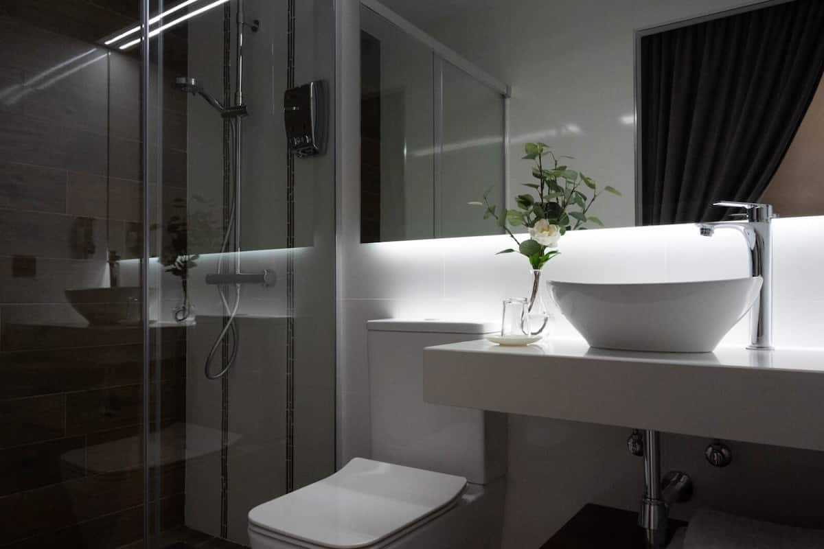 A modern bathroom with a glass-enclosed shower, a white toilet, and a large sink with a bowl.