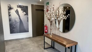 A hallway with a wooden bench, a large black and white artwork, and a round mirror with decorative branches.