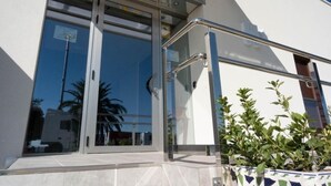 A modern building with large glass doors and a metal railing.