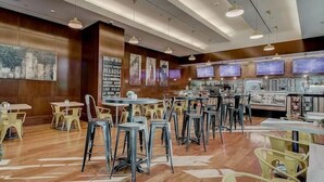 Un restaurant aux murs en bois, doté de nombreuses tables et chaises, et éclairé par des suspensions.