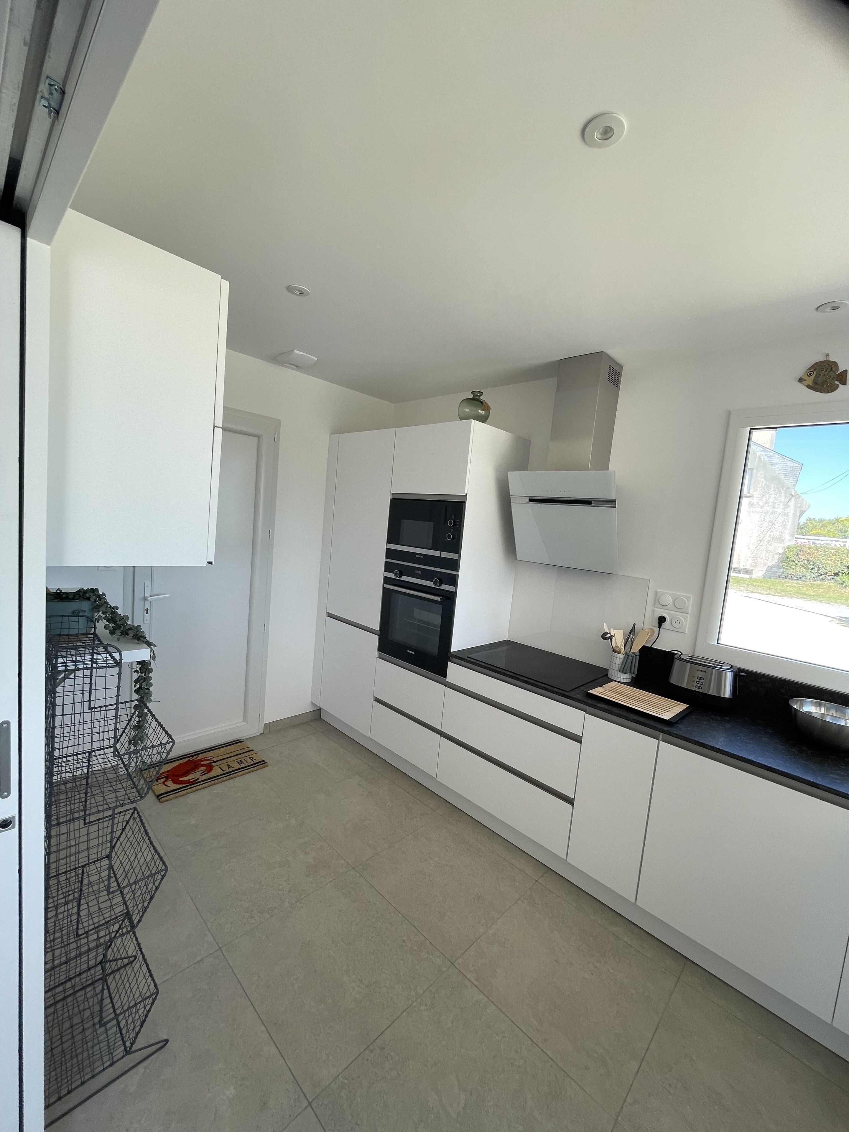 A modern kitchen with white cabinets, a black countertop, and stainless steel appliances.