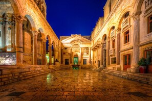 A historic courtyard with classical architecture, featuring columns and arches, and a central building with a green door. - Ana Center Apartment in the Center of Split City (Split)
