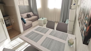 Een kleine woonruimte met een eethoek, kitchenette en een bank.