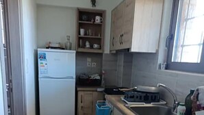 Una cocina compacta con armarios de madera, horno integrado y un lavamanos.