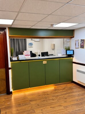 A reception desk with a computer monitor, a telephone, and a sign indicating the reception area. - Middleton Inn, Manchester (Manchester)