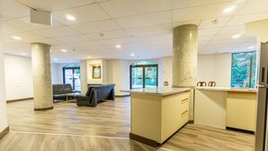 Um hall amplo com balcão de atendimento, área de estar e grandes janelas.