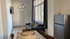 A compact living space with a dining table, sofa, and a refrigerator. - Appartement T3 en Centre Ville a 5 Minutes de la Plage (Saint-Raphaël)