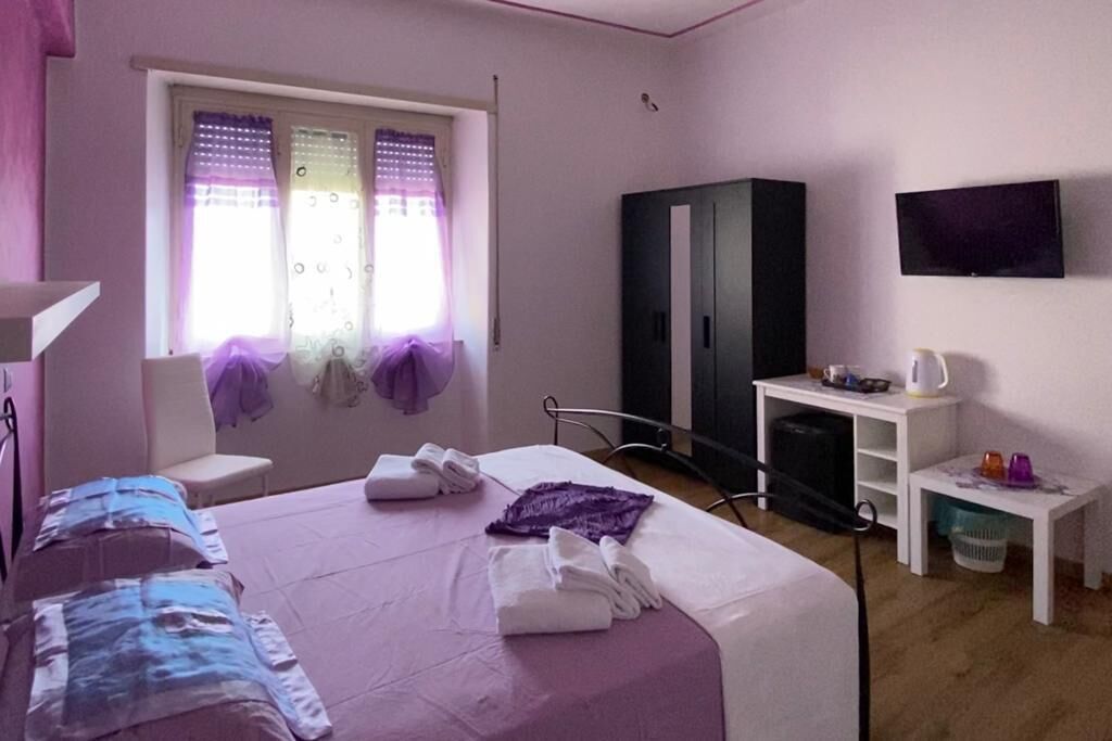 Une chambre avec un lit, une armoire, une télévision et une petite table avec une bouilloire.