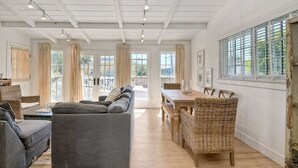 A spacious living room with a grey sofa, a wooden dining table, and wicker chairs.