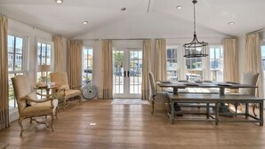 Ein geräumiges Zimmer mit Holzboden, einem Esstisch mit Stühlen und einem Ventilator.