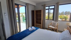 Ein Hotelzimmer mit Bett, einem Sessel, einem Holzboden und Blick ins Freie.
