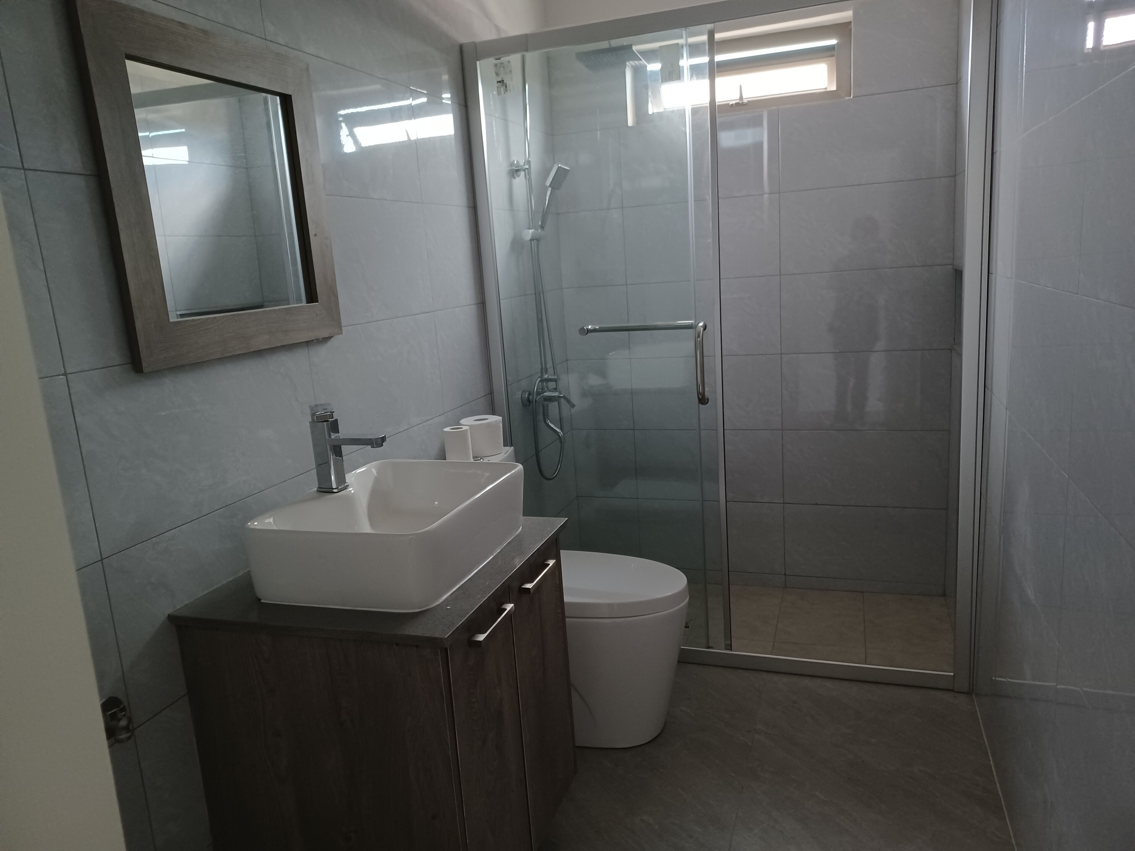 Un bagno moderno con doccia vetrata, lavandino bianco e water.