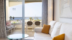 Una sala de estar moderna con un sofá blanco, una mesa de centro de vidrio y un balcón con sillas y una mesa blancos.