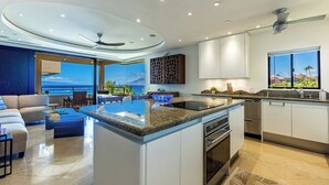 Een moderne keuken met een centraal kookeiland, een inbouwoven en een groot raam met uitzicht op de oceaan.