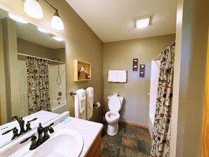 Ein Badezimmer mit Waschbecken, Spiegel, Toilette, Dusche und Handtuchhalter.