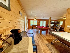 Een houten interieur met een pooltafel, een biljarttafel en een eethoek.