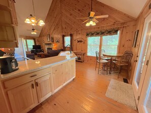 Een houten chalet van binnen met een keuken, eethoek en woonkamer.