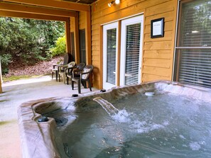 Un jacuzzi en un espacio al aire libre de madera con sillas y una mesa de patio.