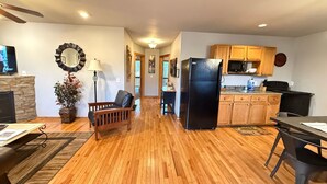 Una cocina moderna con armarios de madera, un refrigerador negro y un comedor con mesa y sillas.