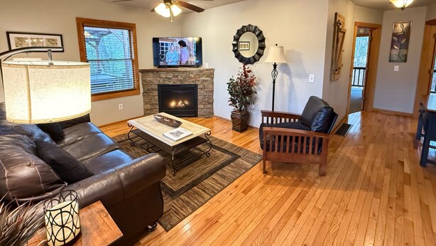 Una sala de estar con chimenea, sofá de cuero, mesa de centro de madera y televisión.