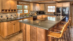 A kitchen with wooden cabinets, a large island with bar stools, and a tiled backsplash.