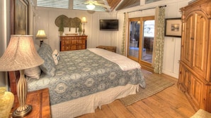 A bedroom with a large bed, wooden furniture, a television, and a balcony with curtains.